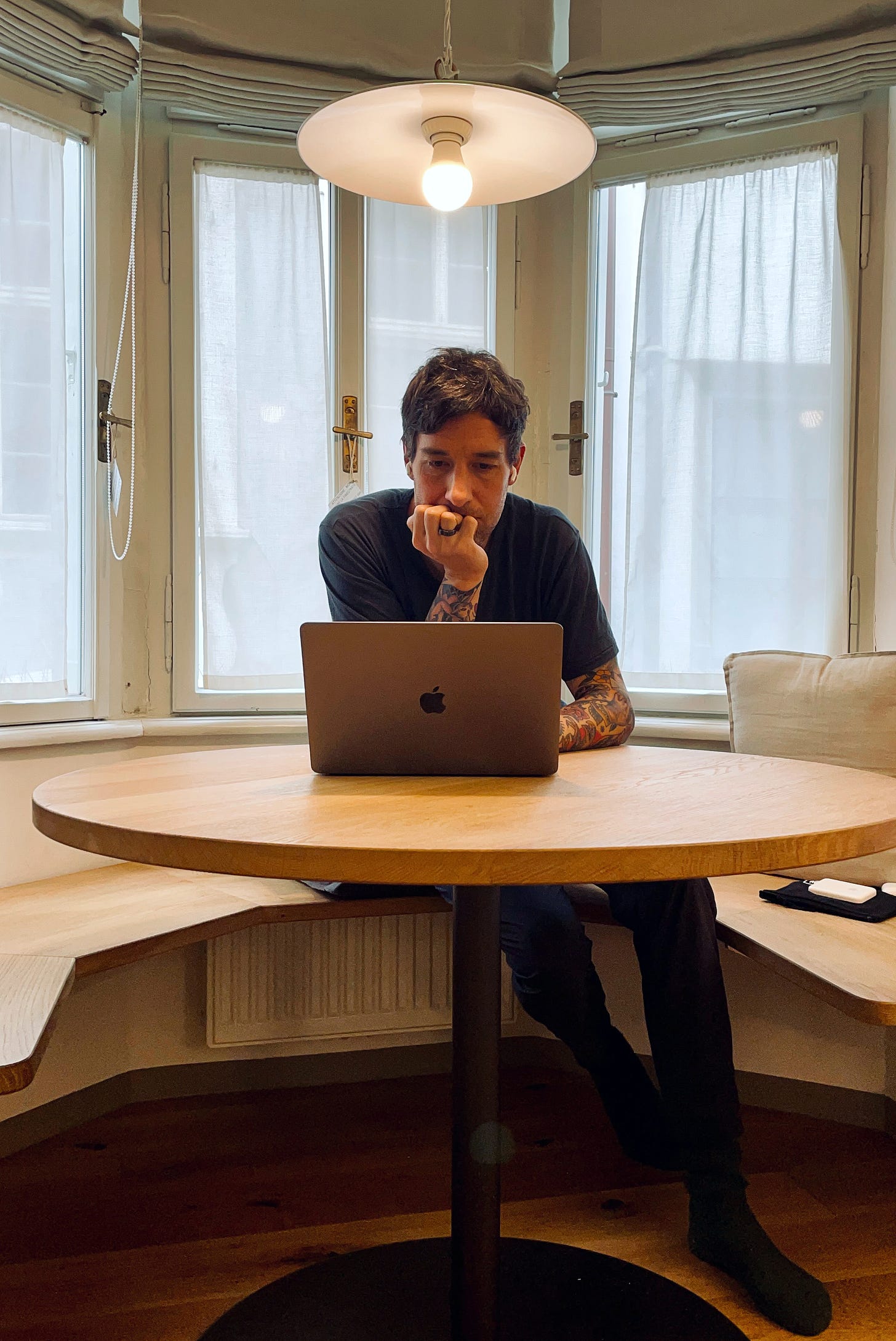Author writing a book, sitting on a round table with his macbook