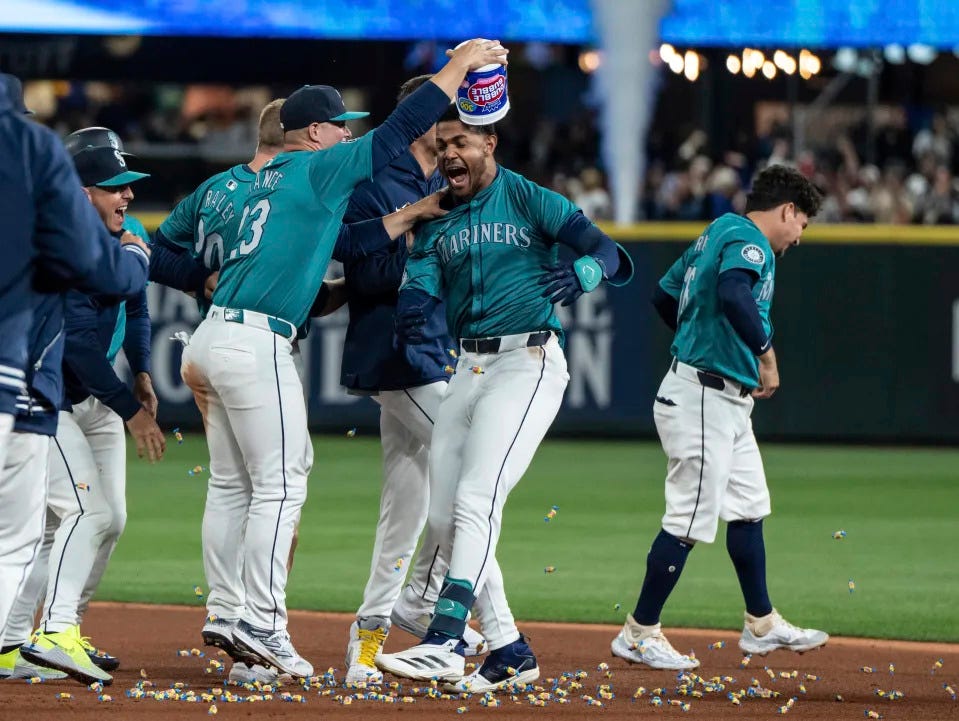 Seattle Mariners' Ty France empties a tub of bubble gum onto the head of the Julio Rodriguez, second from fight, after the team's win in a baseball game against the Boston Red Sox, Saturday, March 30, 2024, in Seattle. (AP Photo/Stephen Brashear)