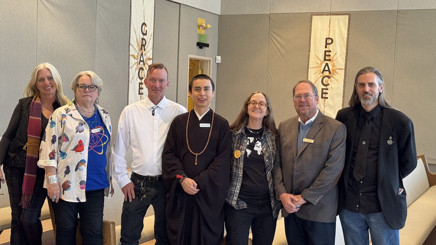 A group of faith leaders and leaders of secular groups from around Arizona stand together in a row at the Secular Summit. Behind them hang banners that read Peace and Grace