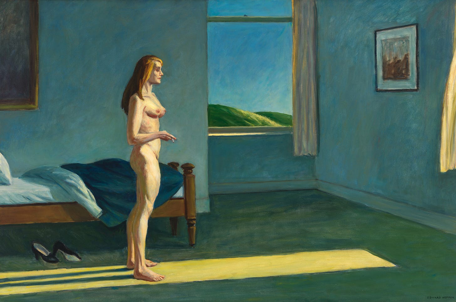 A nude white woman stands in a bluish bedroom and looks out a window as she holds a cigarette.