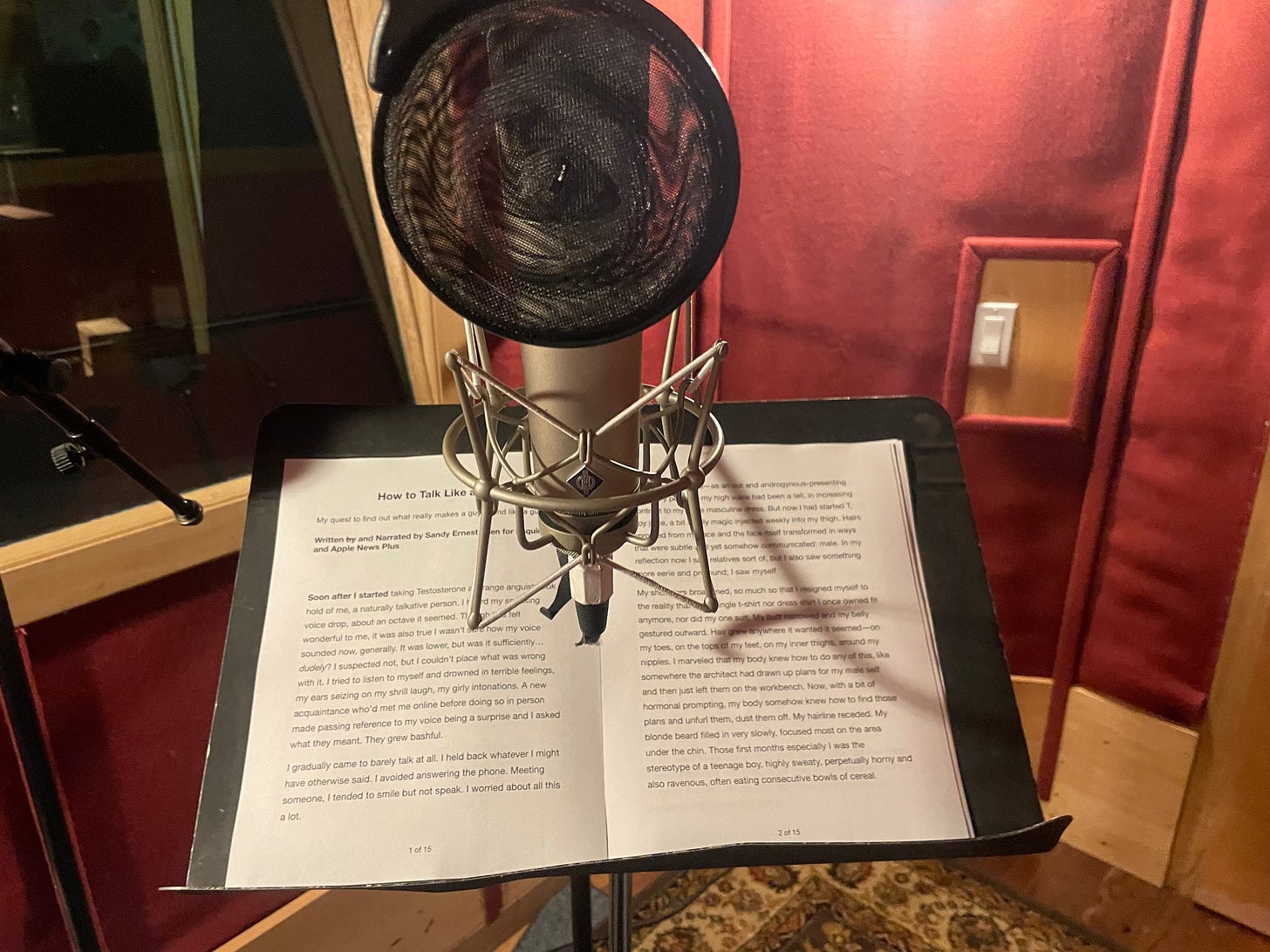 A red recording booth with a mic and stand with the first page of my essay on it