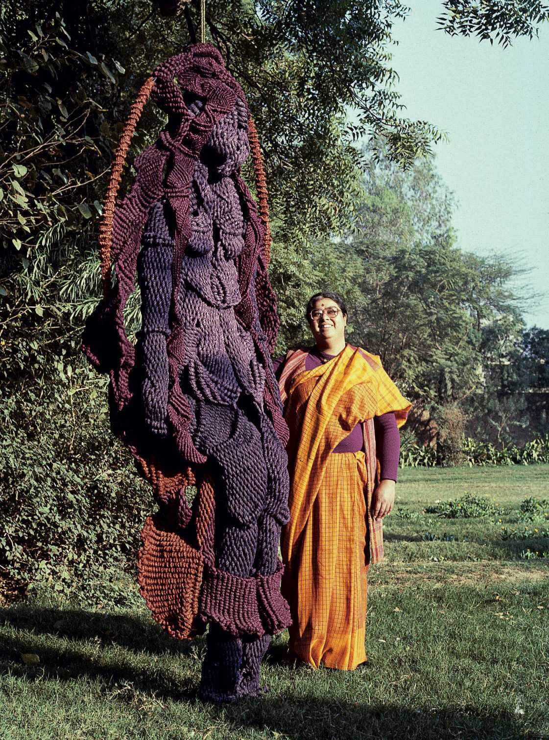 Mrinalini Mukherjee standing with her (twice as tall) jute sculpture