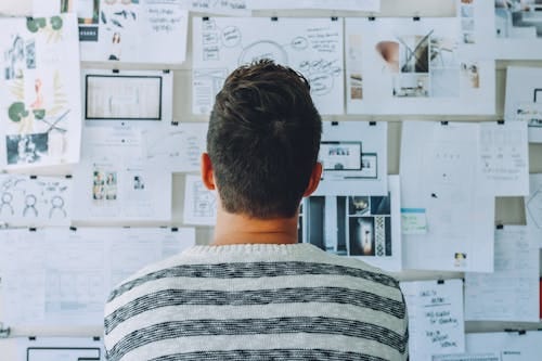 Free Man Wearing Black and White Stripe Shirt Looking at White Printer Papers on the Wall Stock Photo