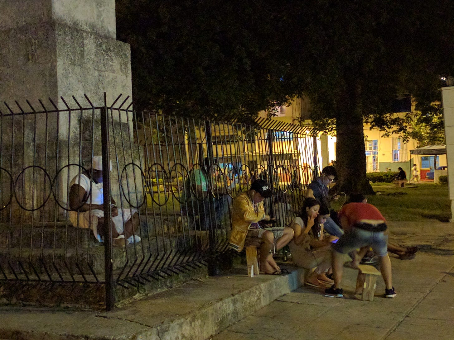 Cubans using their phones in a park at night in Havana