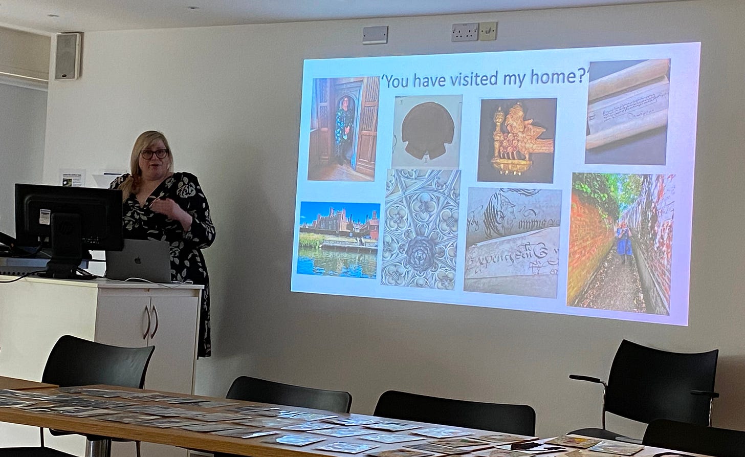 A white woman standing in front of a screen that reads “You have visited my home?” With photographs of places and artefacts from the 16th century.