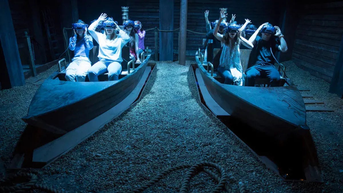 A group of people wearing VR headsets in two boats on a sandy floor