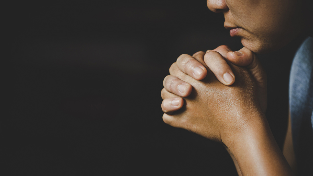 A person praying with folded hands.