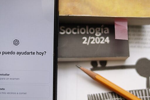 A table with two books, a pen, and a computer open to ChatGPT on the screen.