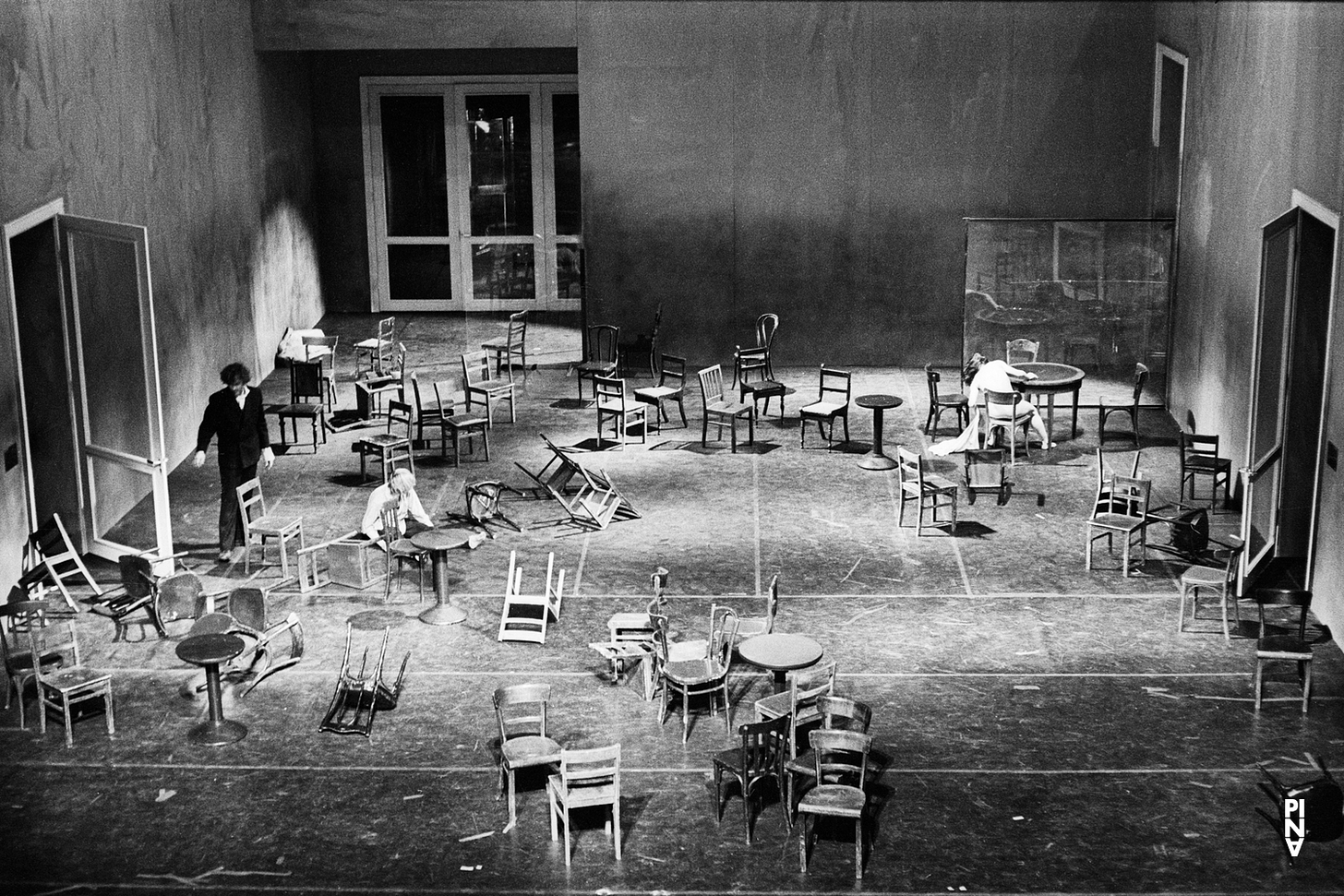 A photograph of a theatre stage scattered with chairs.
