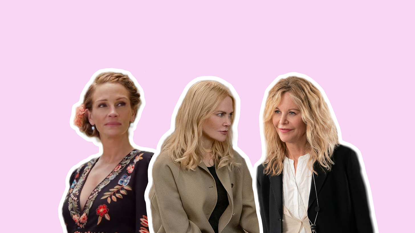 Left to right, Julia Roberts, Nicole Kidman, and Meg Ryan stand against a pastel pink backdrop, a thick white border outlining their silhouettes. On the far left, Julia Roberts wears a black maxi dress with floral embroidery, her red hair pulled into a braided updo with a large pink flower, while in the center, Kidman wears a tan trenchcoat over a black t-shirt with her blonde hair styled down, and on the far left, Ryan wears multiple layers of white linen blouses under a black blazer, also with blonde hair styled down.