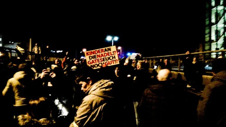 Bilder einer "Querdenken"-Demonstration in Halle (Saale) bei Nacht. Auf einem Schild steht: "Kinder an die Nadel!? Gates euch noch gut!?"