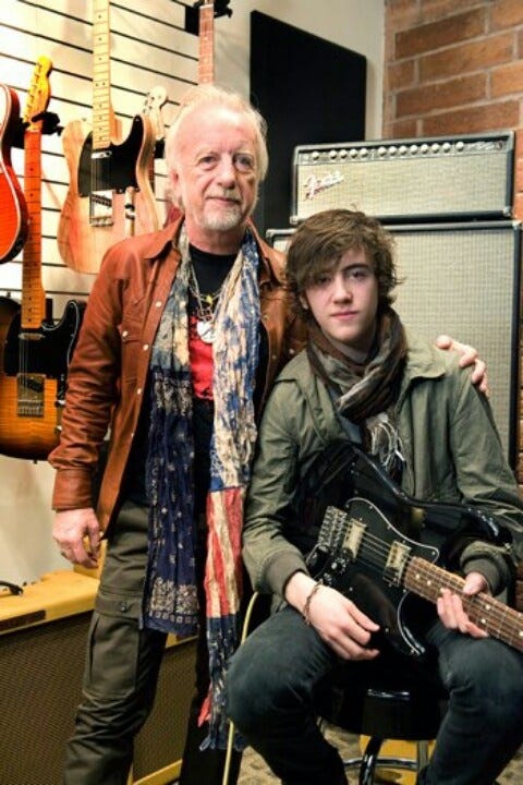 This may contain: two people are posing with guitars in a room