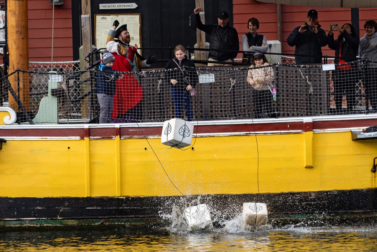 Crates splash into the Fort Point Channel after being tossed overboard by three young museum goers from the merchant vessel Eleanor during a visit to the Boston Tea Party Museum. (Jesse Costa/WBUR)