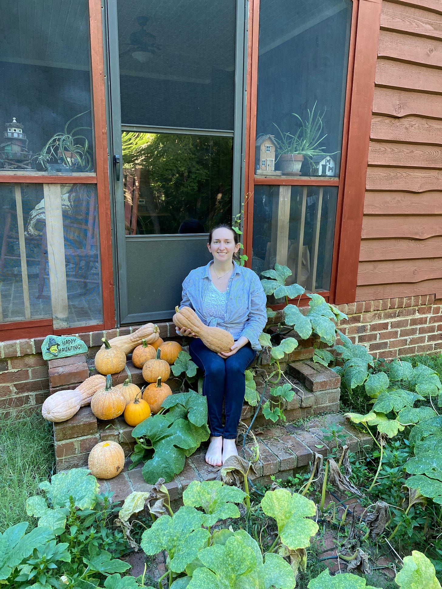 barefoot white woman surrounded by pumpkins on brick steps