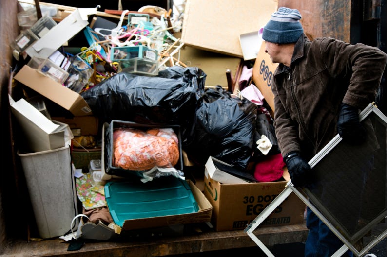 a person tosses junk and trash into an already full trailer