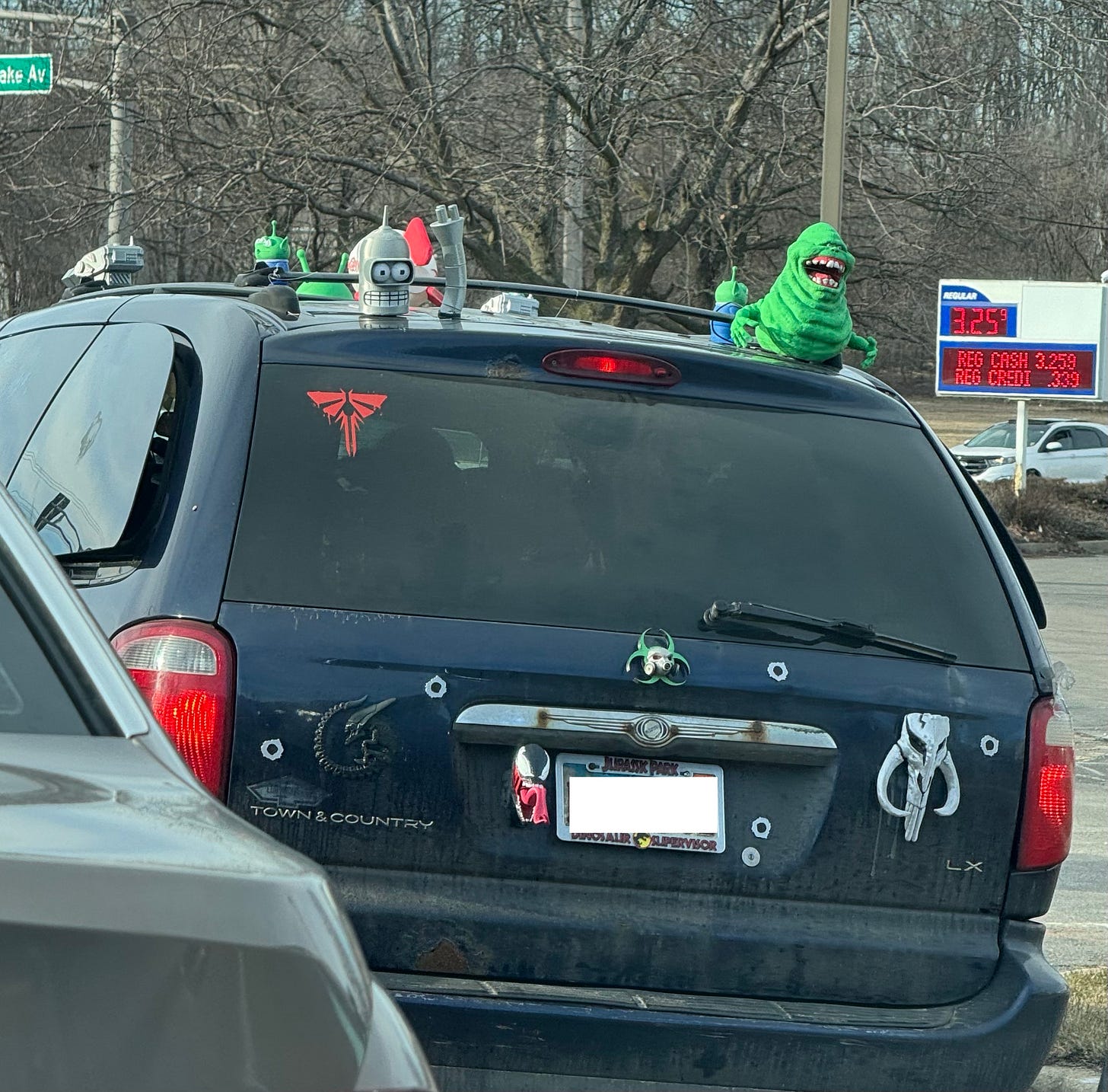 A dark blue Town & Country minivan with a Slimer from Ghostbusters and Bender from Futurama, among other figurines, glued to the roof