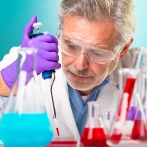 an older male researcher dropping fluid out of a beaker