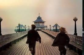 Photo from Never Let Me Go that shows Kathy and Tommy running away from the camera on a pier in Norfolk