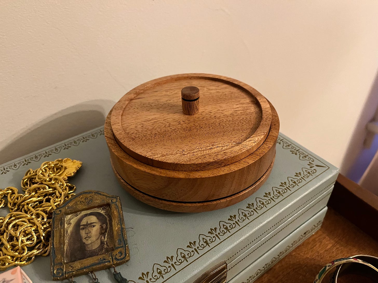 Photo of a circular wood box with a circular lid and a small wooden pull.