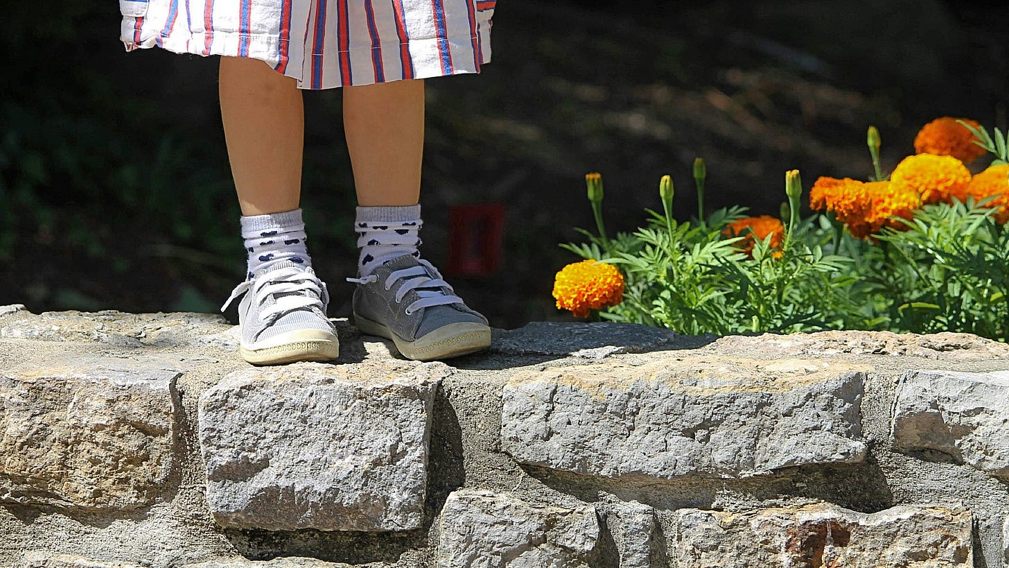 young girl standing on a garden wall young girl standing on a garden wall