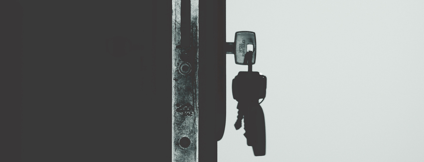 Black and White picture of a key in a keychain unlocking a door lock