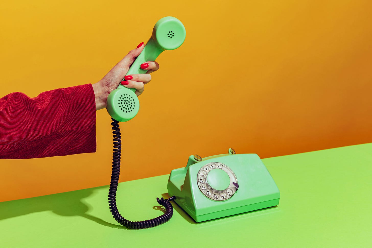 Person holding green rotary phone receiver