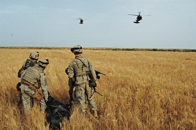 Soldiers engaged in Operation Iron Triangle carry a body bag containing a dead Iraqi near Lake Tharthar on May 9 2006.