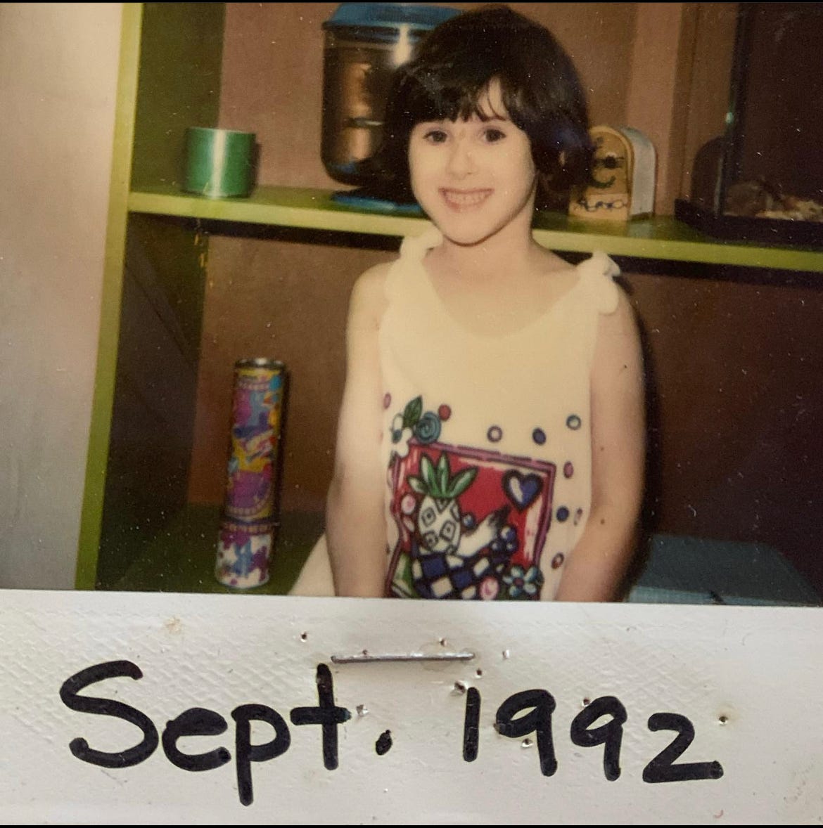 Photo of Lyric, in September 1992, when they were five years old, they are smiling, with medium wavy black hair. 