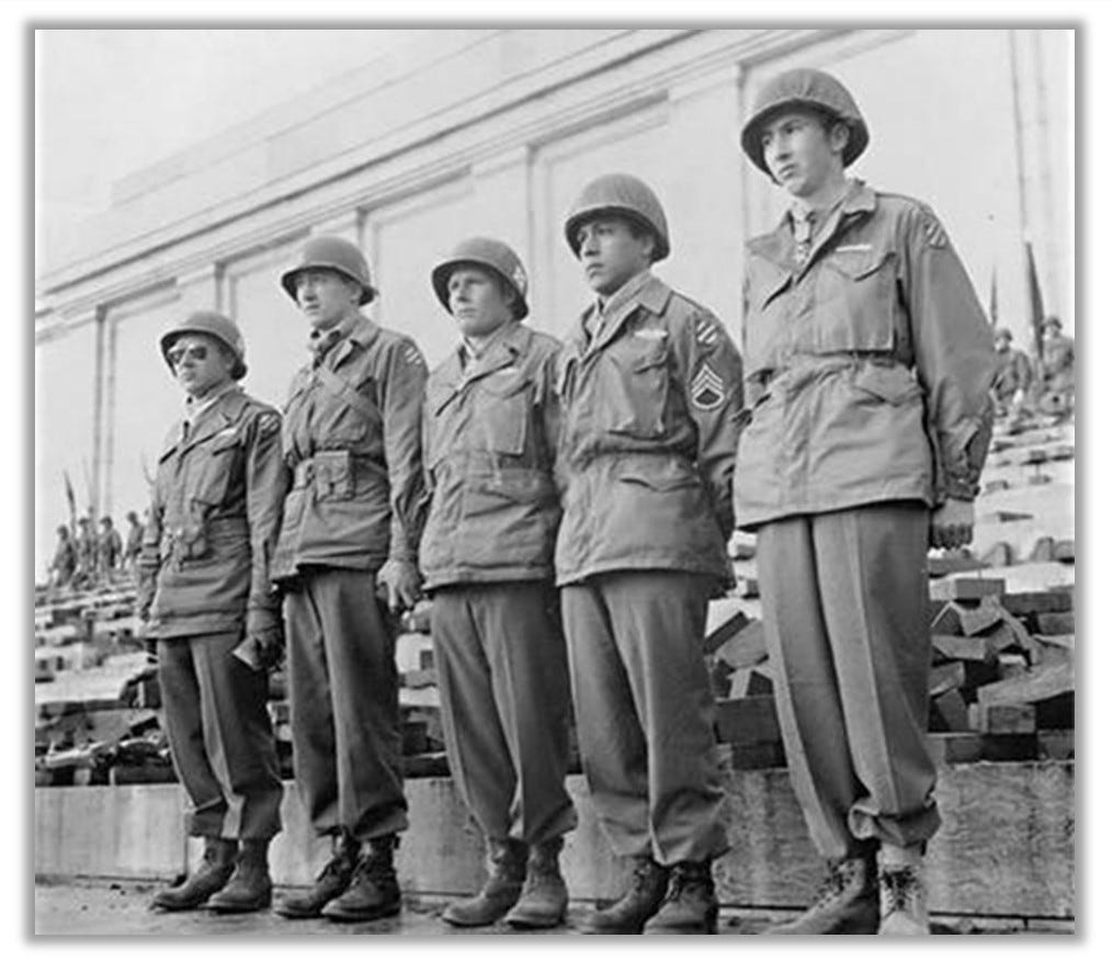 Medal of Honor ceremony for five soldiers from the 3rd Infantry Division (April 1945).  The five soldiers are standing in a line, at attention. The Medal of Honor hangs from each of their necks.