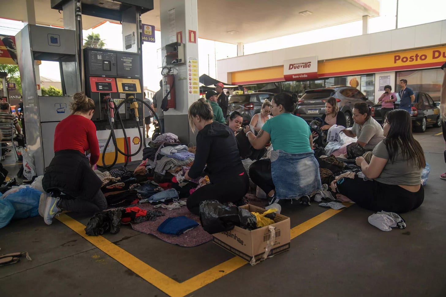 May 5 | Porto Alegre, Brazil. Volunteers provide food, medical attention and clothing to people rescued from flooded houses at a gas station used as a meeting point. Photo: Carlos Fabal / AFP / Getty.