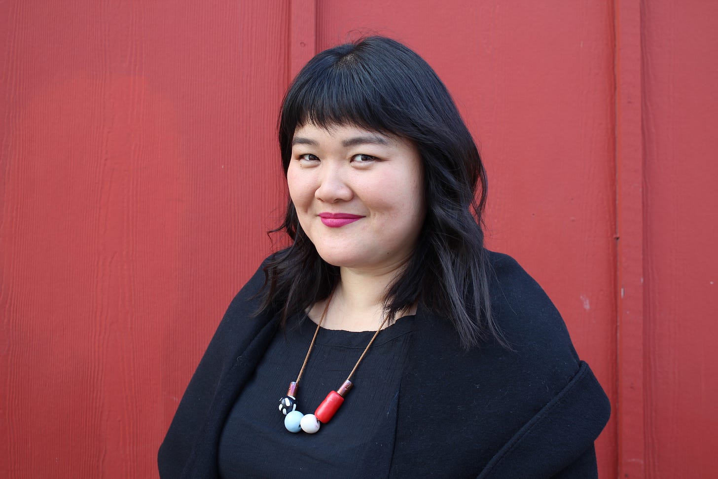author Michelle Yang smiling in black shirt and necklace