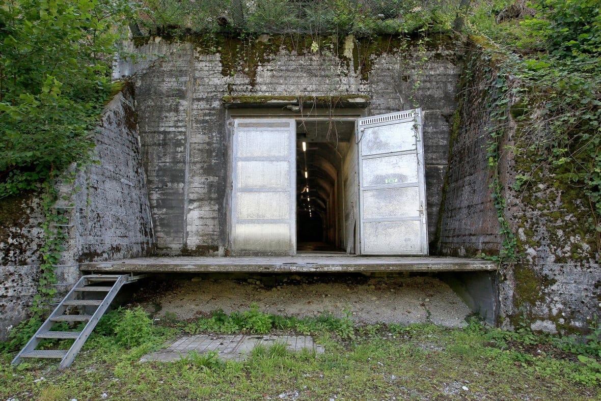 Metal doors built into a rock formation surrounded by grass