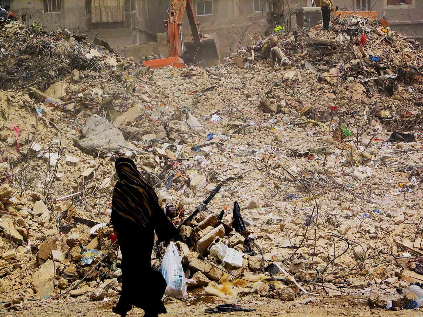 Muslim woman walking with grocery bag past hills of rubble in Shi'ite neighborhood of Southern Beirut, days after the ceasefire of 2006 Lebanon War. Photo by Constantine Markides