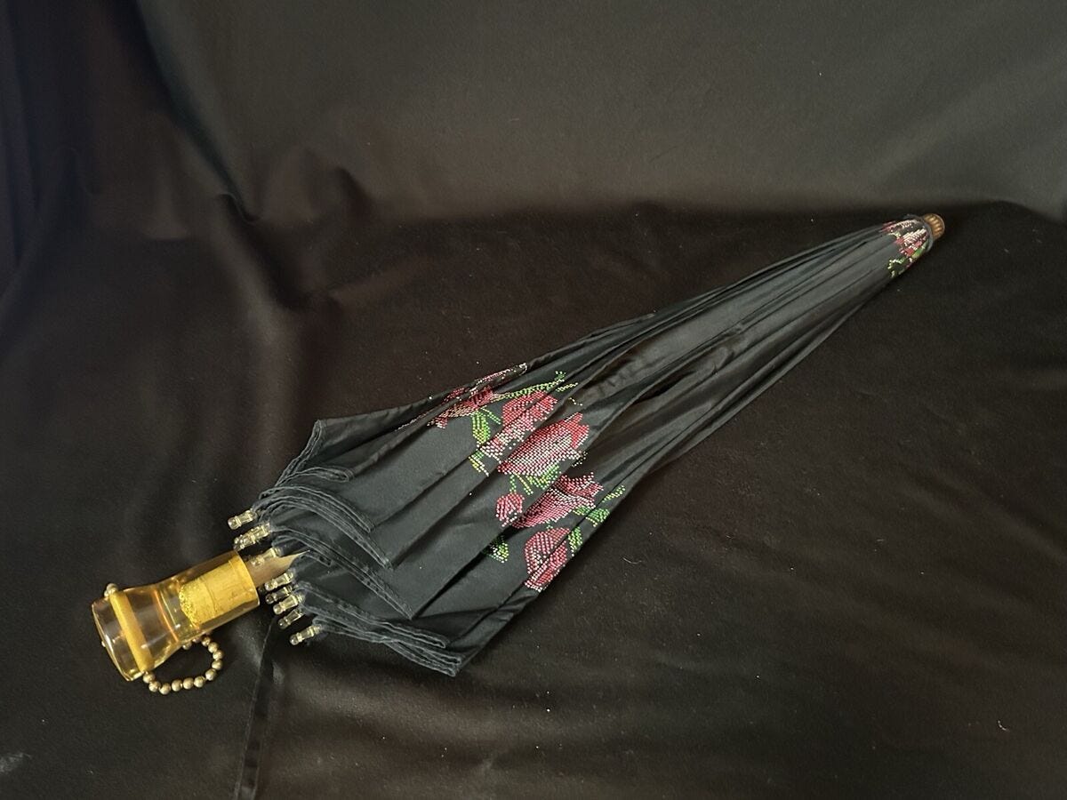 A small black umbrella printed to look as if it has rose appliques on it.