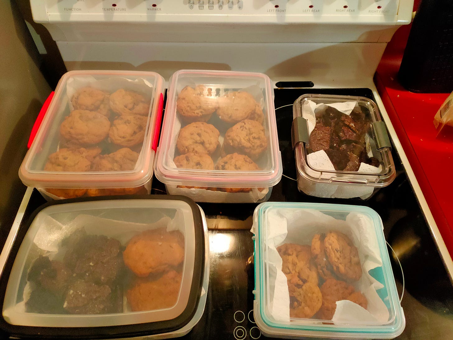 Five plastic containers filled with chocolate chip cookies and brownies
