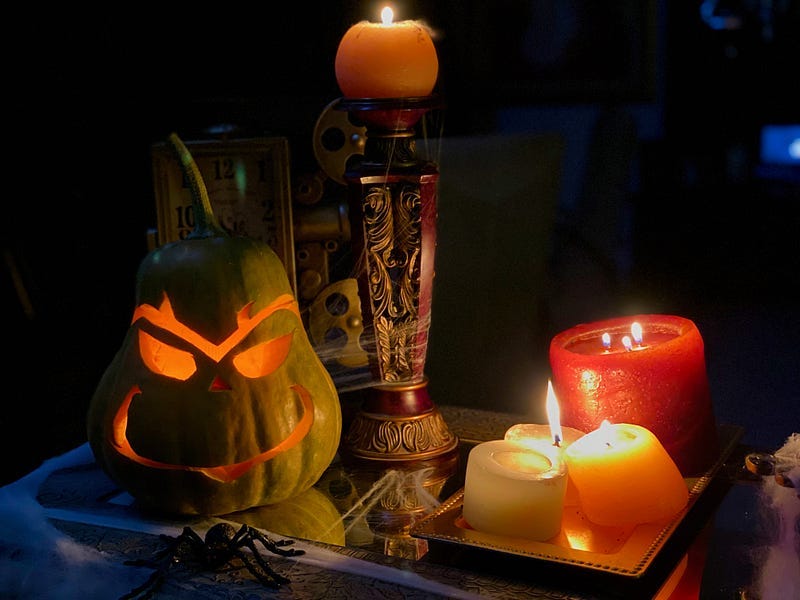 A pumpkin carved in the shape of the “Grinch” character next to some candles.