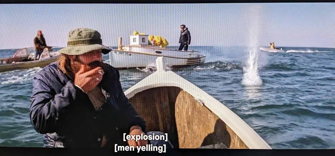 A fisherman smoking a cigarette, having cast a small explosive into the water behind him.