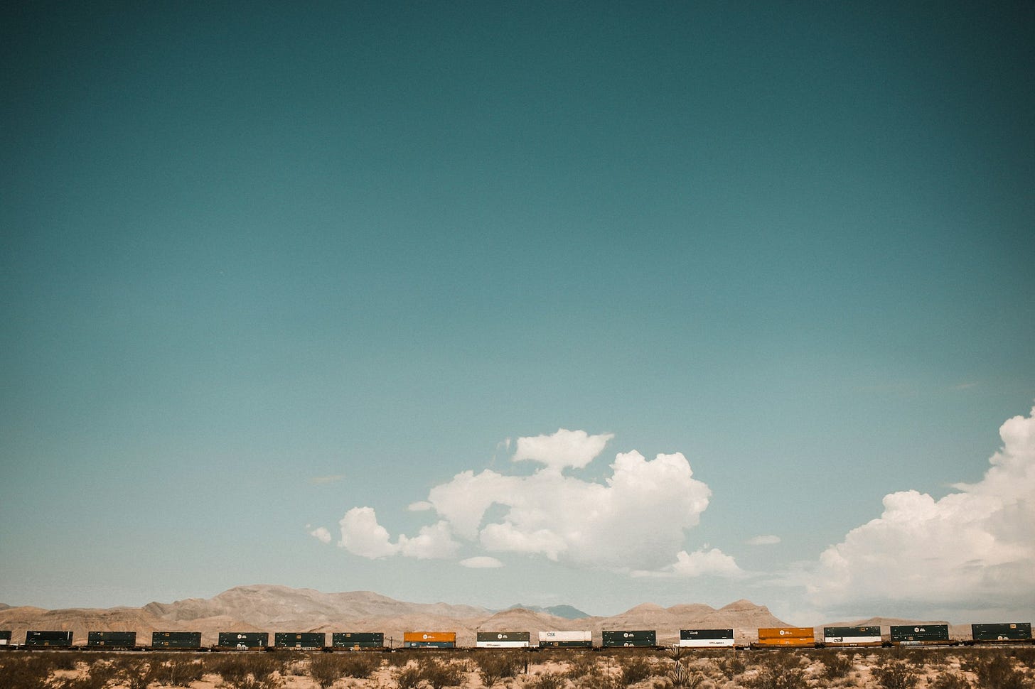 A train with boxcars rolling across an open landscape with clouds A train with boxcars rolling across an open landscape with clouds