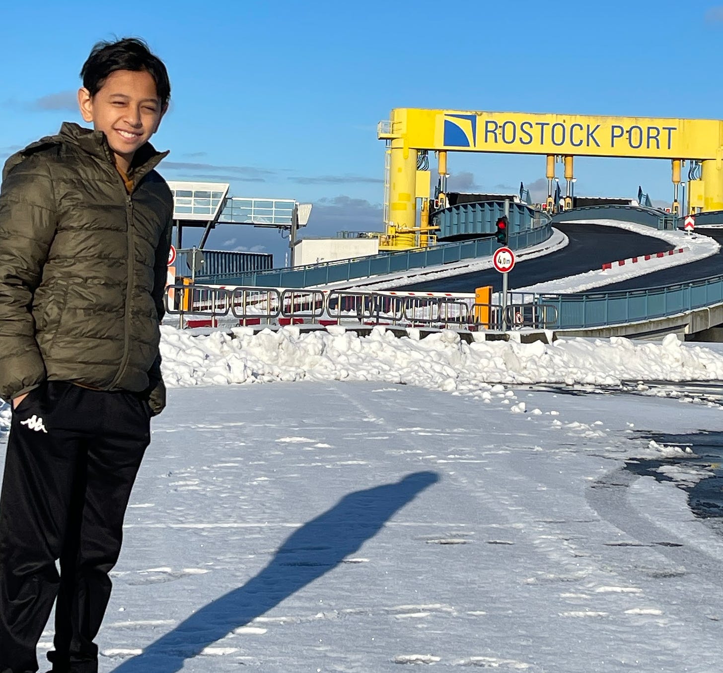 Child standing in front of a sign titled "Rostock Port" 
