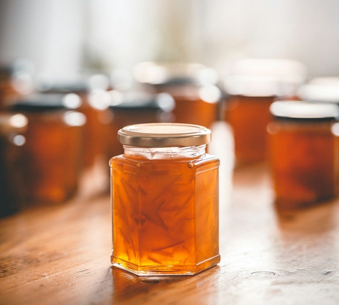 a wooden table topped with lots of jars of honey