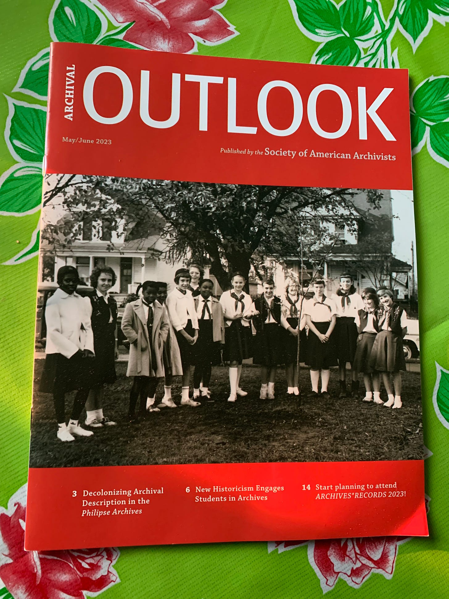 Cover of magazine with black and white images of girls standing around a recently planted tree