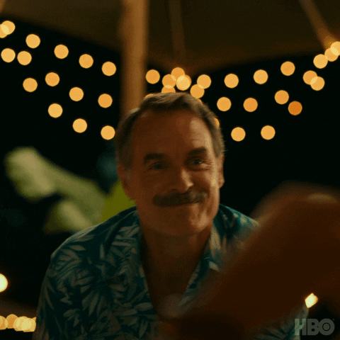 A gif of Armond from White Lotus saying, "Please enjoy" to a guest