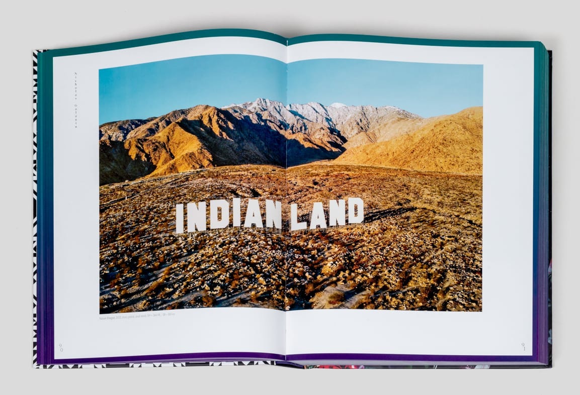 Inside spread of Indigenous Present book with "INDIAN LAND" spelled out ilke the Hollywood sign on an expanse of natural landscape.