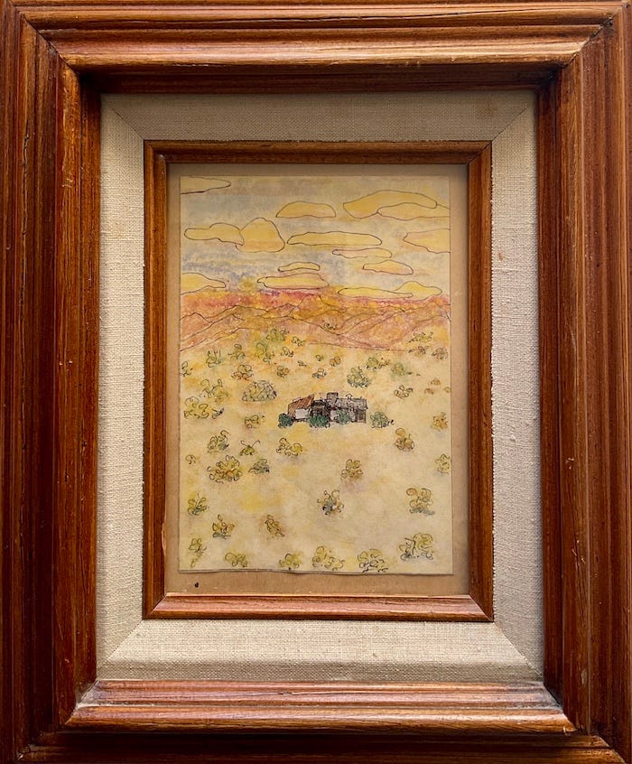 Framed pen&ink watercolor drawing by Sherry Killam Arts of a cabin surrounded by pale desert colors with sparse vegetation against a background of mountains, sky, and clouds.