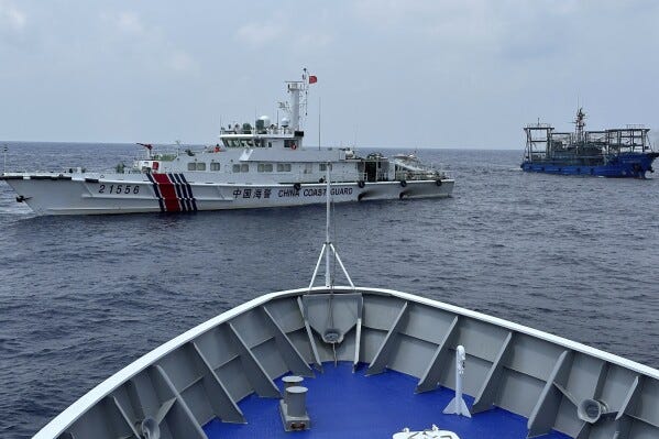 A Chinese coast guard ship, left, with a Chinese militia vessel, right, blocks Philippine coast guard ship, BRP Sindangan as it tried to head towards Second Thomas Shoal at the disputed South China Sea during rotation and resupply mission on Wednesday, Oct. 4, 2023. (AP Photo/Joeal Calupitan)