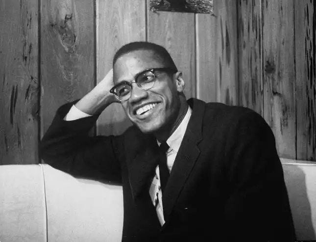 a black and white image of malcolm x smiling