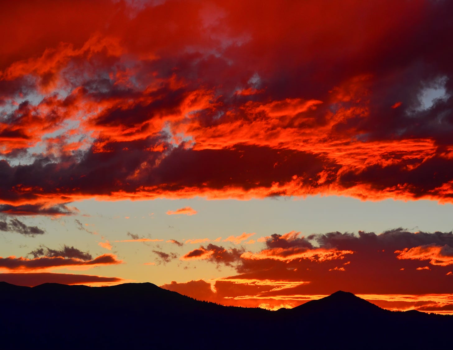 Red clouds at sunset with mountains on the horizon