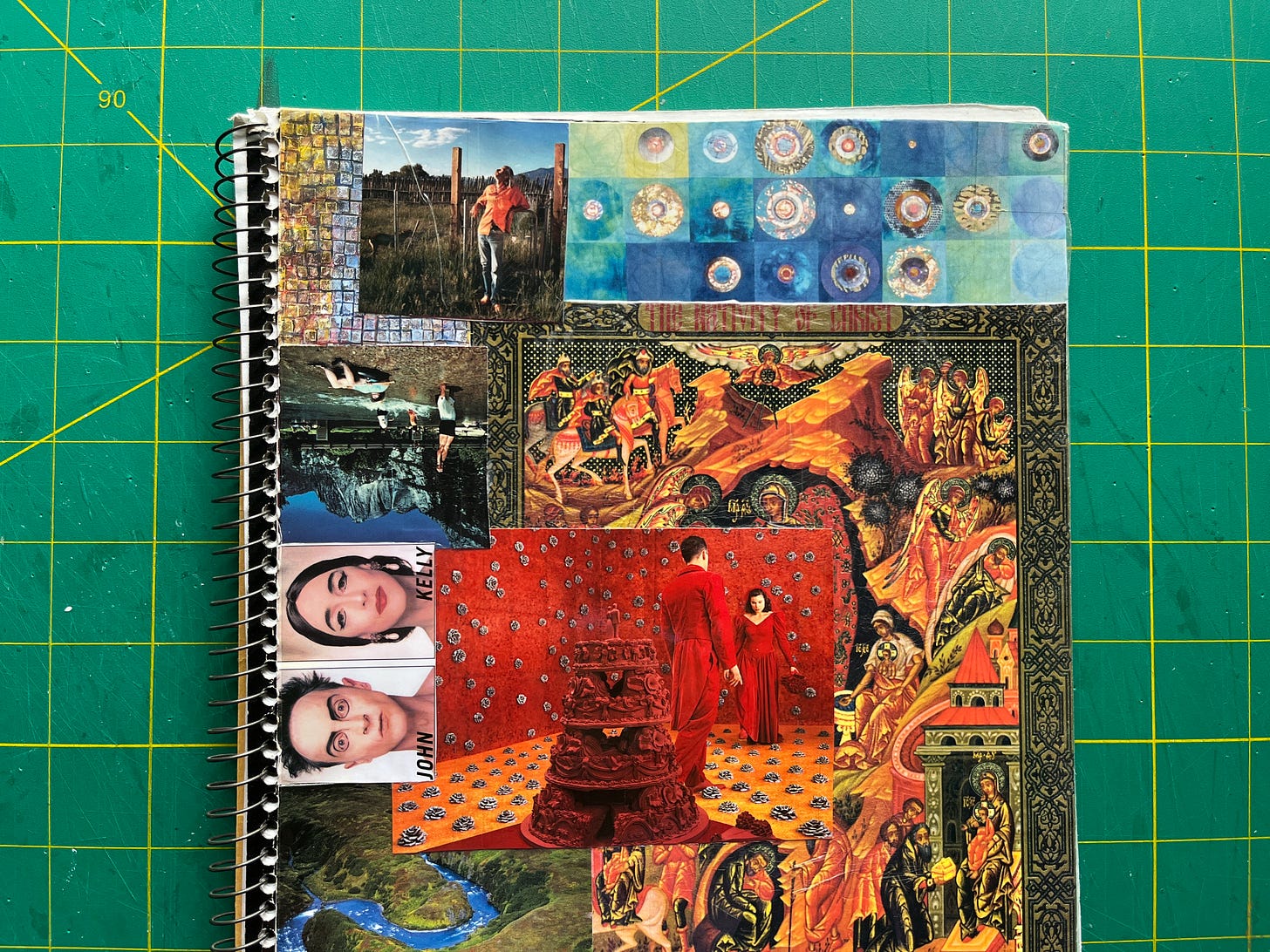 A spiral bound notebook sits on a gridded cutting mat. Its cover is collaged with colorful pictures from magazines.