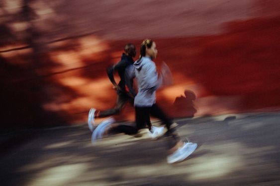 A blurry image of two humans running in athleisure.