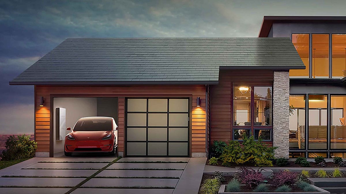 A detatched, single-family home with a two car garage. A Tesla car and battery is visible through an open garage door.